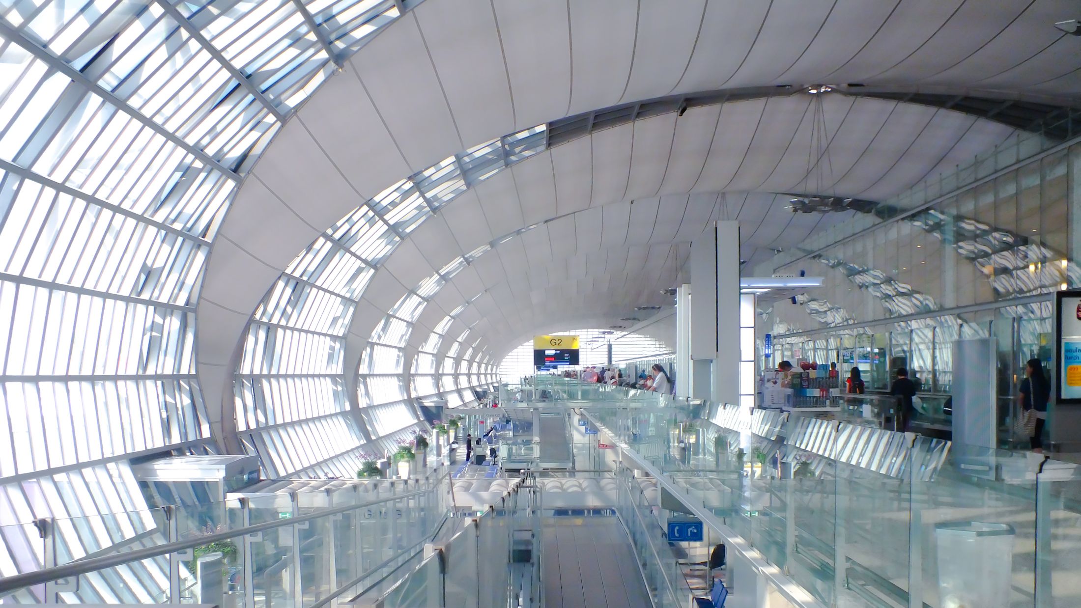 A bright international airport terminal with a curved glass roof
