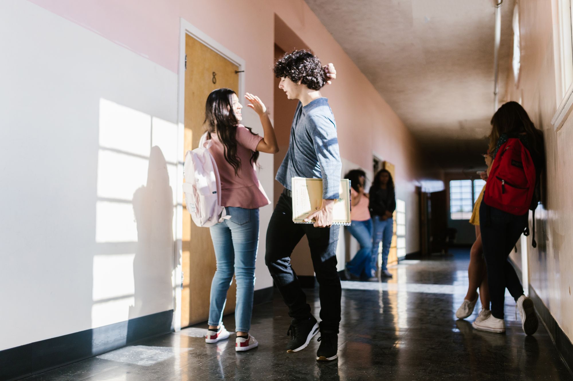 Students talking in a bright American high school hallway